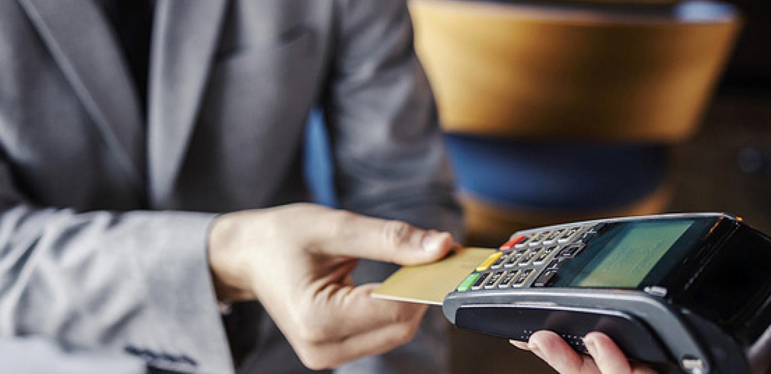 man in blazer paying for check with card machine
