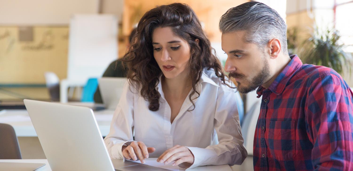 Two coworkers review sales leads on a laptop