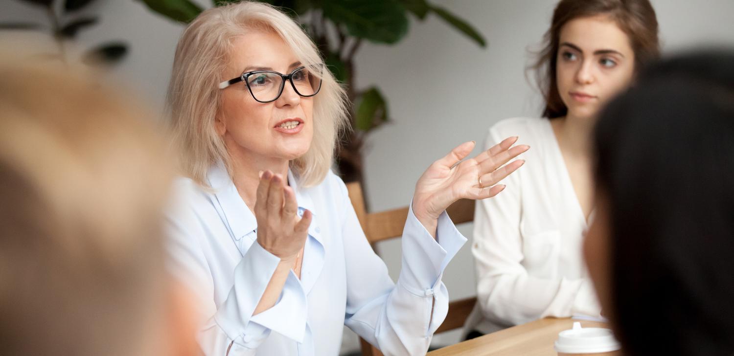 Mature businesswoman speaks to a group of mentees