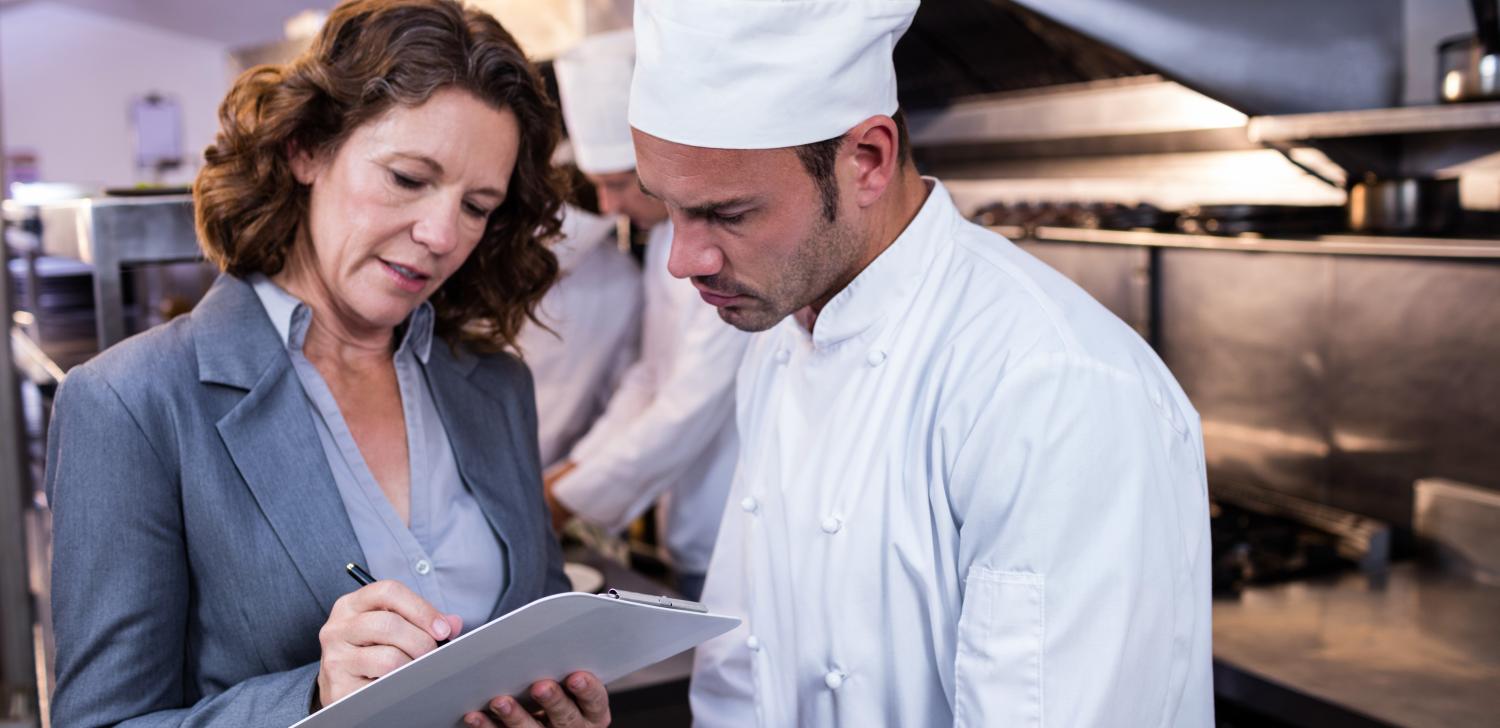 Restaurant owner talks over notes with chef